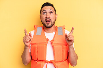 Young latin beach watcher wearing a lifejacket isolated pointing upside with opened mouth.