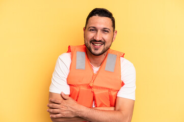 Young latin beach watcher wearing a lifejacket isolated laughing and having fun.