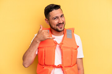 Young latin beach watcher wearing a lifejacket isolated showing a mobile phone call gesture with...