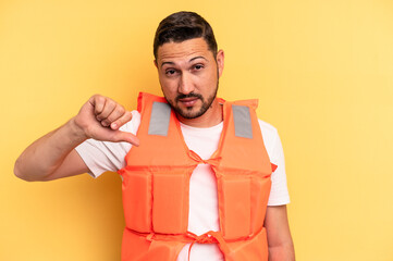 Young latin beach watcher wearing a lifejacket isolated showing a dislike gesture, thumbs down....