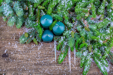 Background for a gift card. New Year's composition of snow-covered fir branches with cones, icicles and green candles. copy space