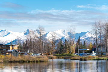 Fototapeta na wymiar Seaplanes at the base on Lake Spenard with snow cap Chugach Mountain and row of dormant trees in early fall in Anchorage, Alaska