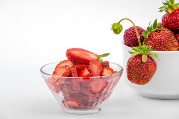Fresh strawberries, a plate with sliced strawberries on a white background close-up