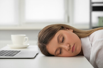 Tired young woman sleeping at workplace in office