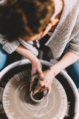 Working on pottery wheel in ceramics workshop creating ceramic ware.