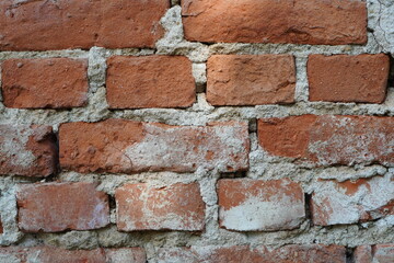 Closeup of old red brick wall with layers of unequal bricks glued with cement