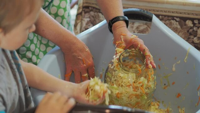 Home canning. The child helps to preserve cabbage and puts it in a glass jar. Hand held. Siberia.
