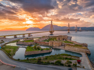 Aerial view of Rio (Rion) fortress near Patras and the Rion-Antirion bridge Greece protecting and crossing the entrance to the Gulf of Corinth with magical colorful sunset - obrazy, fototapety, plakaty