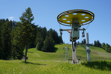 Ski lift with yellow impeller for tow rope in spring time in Melchsee-Frutt region. Hills are...