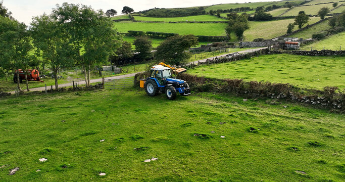 Aerial photo of a Blue New Holland Ford 8240 Tractor Cutting a hedge with a McConnel on a farm in UK Antrim Northern Ireland 30-10-22