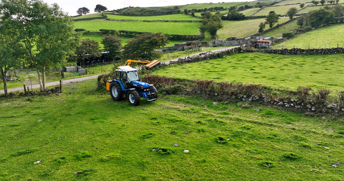 Aerial photo of a Blue New Holland Ford 8240 Tractor Cutting a hedge with a McConnel on a farm in UK Antrim Northern Ireland 30-10-22