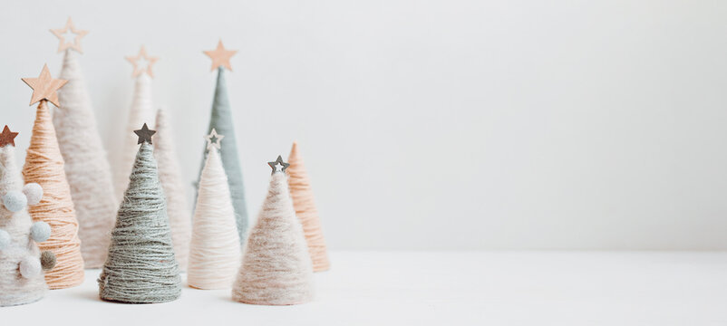 Christmas craft background with handmade yarn cone xmas trees in natural colors.