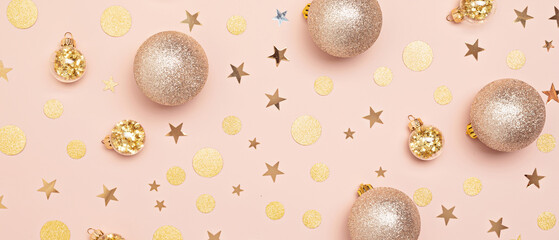 Golden christmas ornaments and confetti over pink pastel background.