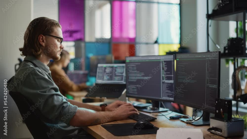 Poster Caucasian Male Software Engineer Coding on Desktop Computer With Multiple Displays in Creative Office. Young Handsome Man Writing Code For Mobile Application In Tech Start-Up Company.