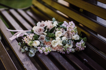 Lush beautiful bouquet with roses, eucalyptus, eustoma, peonies lies on a brown wooden bench