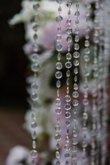 Room decor, transparent beads hanging on the background of decoration with flowers