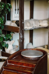 Empty potter's wheel against the background of a rack with clay products in a pottery workshop