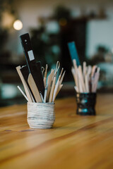 Tools for creating pottery from clay, brushes for coloring clay products stand on a wooden table