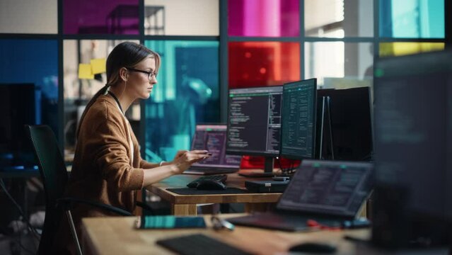 Young Caucasian Woman Programming On Desktop Computer With Two Monitors Setup in Spacious Office. Female Software Developer Creating SaaS Platform For Businesses in Innovative Start-up Company.