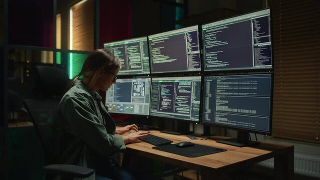 Female Programmer Coding on Desktop Computer With Six Monitors Setup in Dark Office. Smart Caucasian Woman Monitors Data Protection System For Cyber Security Department IT Company