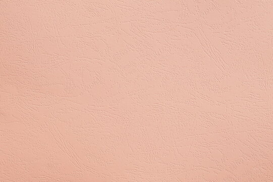 Closeup photo of cardboard sheet surface in soft pink color. Unicolor indented texture background.