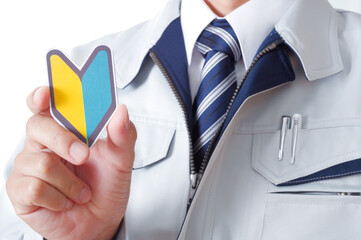 初心者マークを持つ作業服の男性