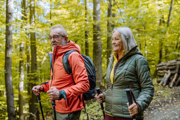 Happy senior couple hiking in autumn forest.