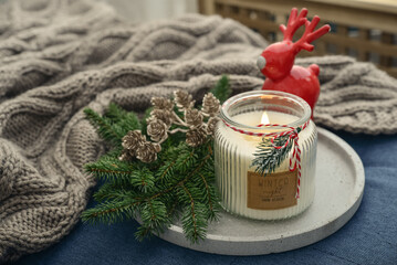 Red ceramic deer and candle in jar with fir tree branches