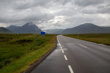 A82 road. View of the mountains in Glencoe, Scotland. Poster announcing open all year