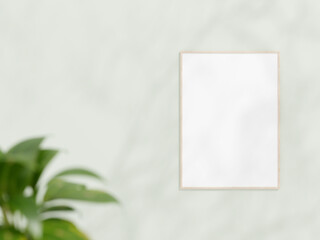 Vertical wooden frame mockup on white wall. Poster mockup. Clean, modern, minimal frame. Empty frame Indoor interior, show text or product. frame mockup with shadow and plant. 3d rendering.