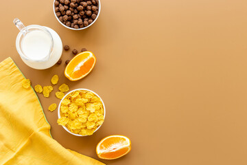 Bowls of corn flakes with milk and oranges for breakfast