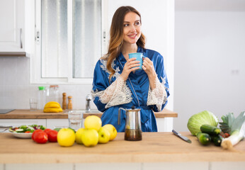 Attractive woman wearing in housecoat making coffee at kitchen