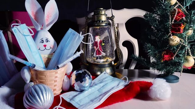 Rabbit symbol of 2023 new year with protective face mask, Christmas lantern with Santa Claus and New Year tree in dark. Safe holiday celebration concept during coronavirus pandemic. 