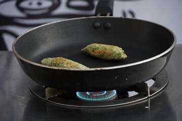 Closeup shot of Snack jalapenos on a pan set on a gas