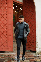 Obraz premium Stylish boy with a fashionable hairstyle in a leather jacket posing on the street in motion.