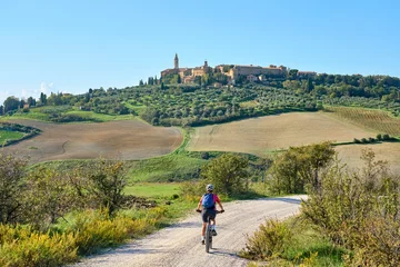 Fotobehang Toscane nice senior woman riding her electric mountain bike  in the Ghianti area beow the skyline of the medieval city of Pienza , Tuscany , Italy  © Uwe