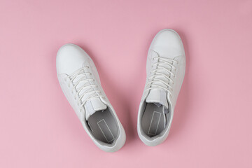 Pair of new white sneakers on pink background