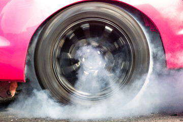 Car wheel spinning wheel and smoking, Race car doing lot of smoke on race track, Car wheel drifting and smoking on track.