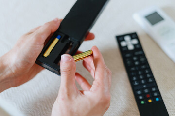 woman changing battery in tv remote control, closeup