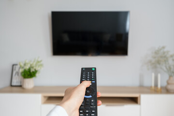 woman watching tv with remote control indoors - obrazy, fototapety, plakaty