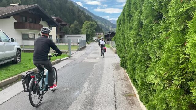 Cyclists on a lane in Tyrol, Austria showing a village house.