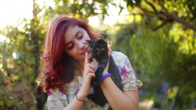 Red hair girl playing with domestic cats outdoor