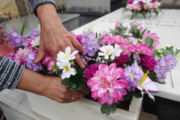 Hands placing flowers on a grave