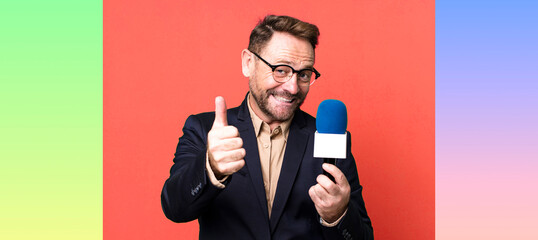 middle age man feeling proud,smiling positively with thumbs up. journalist and a microphone concept