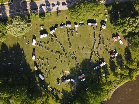 Aerial Shot Of People And Parked Cars Circled In A Field