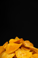 Delicious crispy potato chips with spices on a black background, place for text