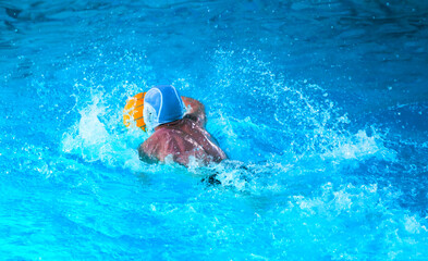 Young men play water polo in a swimming pool