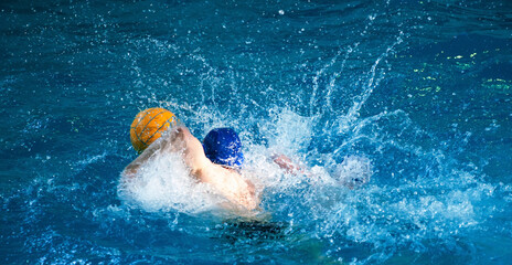 Fototapeta premium Young men play water polo in a swimming pool