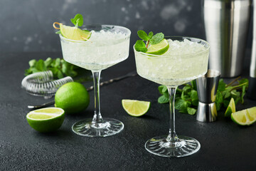 Margarita cocktail with lime, tequila, mint and ice on dark table with amazing backlight, copy space. Classic Margarita or Daiquiry Cocktail. Bar card or counter concept. Selective or soft focus.