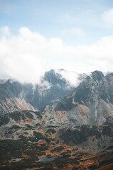Brown and gray high rocky mountains merged with clouds during daytime